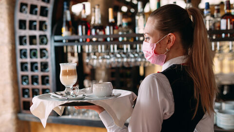 Eine Kellnerin mit Maske und Tablett