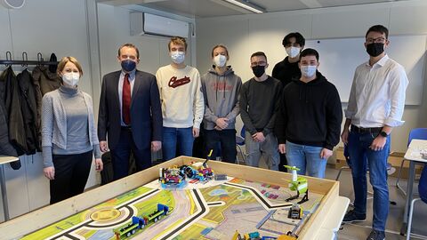 Kultusminister Lorz macht sich vor Ort ein Bild von der Initiative Kultusminister Lorz gemeinsam mit Schülerinnen und Schüler der First Lego League Challenge. Sie stehen um einen Tisch herum wo die Roboter getestet werden.