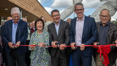 Eröffnung Bildungs- und Sportcampus Bürstadt Ministerpräsident Rhein (Mitte) mit weiteren Beteiligten bei der Eröffnung des Bildungs- und Sportcampus. Sie stehen nebeneinander vor einem roten, mit Schleife gebundenen Band und schneiden mit Scheren das Band durch.