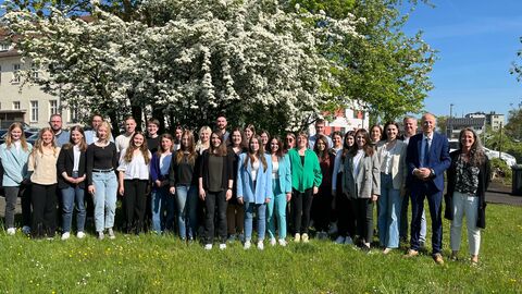 Eine Gruppe junger Personen steht gemeinsam mit Kultusminister Schwarz auf einer Wiese vor einem Baum zum Gruppenfoto.