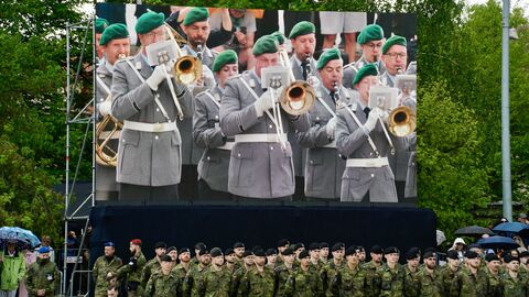 Aufstellung Panzerbrigade 45 in Litauen Eine Gruppe Soldaten steht vor einem Bildschirm, auf dem das Bundeswehrorchester zu sehen ist.