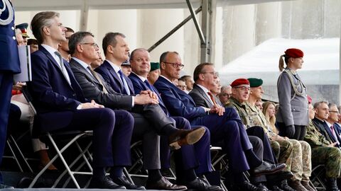 Feierliche Aufstellung Panzerbrigade 45 in Litauen Ministerpräsident Rhein, Bundeskanzler Merz, Verteidiungsminister Pistorius und weitere Personen sitzen zusammen.