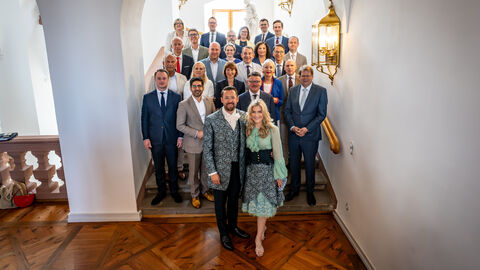 Die Ministerinnen und Minister Hessens stehen auf einer Treppe in einem historischen Gebäude.