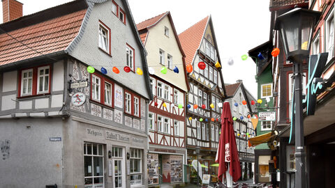 Eine Fachwerkhäuser-Zeile in Alsfeld; das Haus in der Mitte, beige-hellbraun gehalten mit historischen Fotos im Schaufenster im Erdgeschoss, ist das Preisträgerobjekt