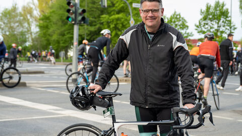 Radklassiker Eschborn-Frankfurt Ministerpräsident Rhein steht neben seinem Rennrad und lächelt in die Kamera