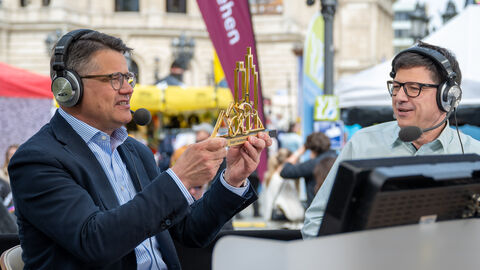 Radklassiker Eschborn-Frankfurt Ministerpräsident Rhein mit Kofhörern im Gespräch mit einem anderen Mann mit Kopfhörern