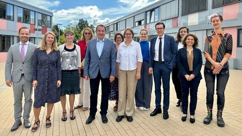 Kultusminister Lorz mit einer Gruppe Personen vor einem Gebäude. Alle stehen nebeneinander und lächeln.
