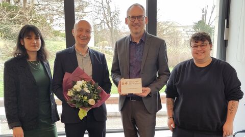 Sozialminister Kai Klose zeichnet Knud Wechterstein als Menschen des Respekts aus Sozialminister Kai Klose und Knud Wechterstein stehen mit zwei weiteren Personen vor Fenster. Kai Klose hält Urkunde in der Hand.