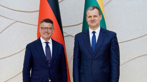 Ministerpräsident Boris Rhein trifft in Vilnius den litauischen Regierungschef Gintautas Paluckas. Zwei Männer stehen vor der deutschen und litauischen Landesflagge nebeneinander.