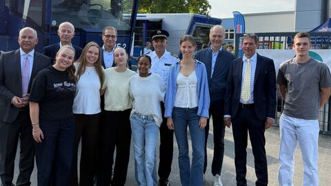 Enkelhelden  Mehrere Erwachsene sowie Schülerinnen und Schüler stehen vor Polizei-LKW