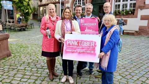 Pinktober Mehrere Personen stehen zusammen und halten ein Plakat in den Händen